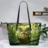 An owl with green feathers perched on the branch leather tote bag