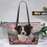 Black and white border collie sits in the foreground amidst blooming flowers leather tote bag