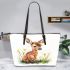 Cute baby deer sitting in the grass leather totee bag