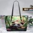 Cute baby panda is eating bamboo leaves in the forest leather tote bag