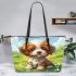 Cute brown and white puppy is sitting on the grass leather tote bag