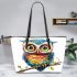 Cute colorful owl with big eyes sitting on a tree branch leather tote bag