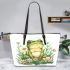 Cute frog sitting on the grass with flowers leaather tote bag