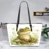 Cute frog sitting on the ground with flowers leaather tote bag