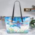 Dragonfly is flying over the grass leather tote bag