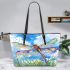 Dragonfly is flying over the grass leather tote bag