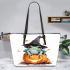 Frog wearing a black witch's hat sitting on top of a halloween pumpkin leaather tote bag