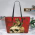 Green frog playing the banjo on top of human skull leaather tote bag