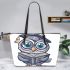 Grey owl with big eyes wearing glasses and graduation hat holding leather tote bag