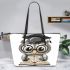 Grey owl with big eyes wearing glasses and graduation hat holding leather tote bag