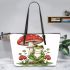 Red and white mushroom with green frog sitting on it leaather tote bag