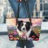 Black and white border collie sits in the foreground amidst blooming flowers leather tote bag