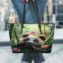 Cute baby panda is eating bamboo leaves in the forest leather tote bag