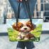 Cute brown and white puppy is sitting on the grass leather tote bag