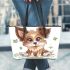 Cute cartoon puppy sits on the ground with its paws spread leather tote bag