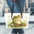 Cute frog sitting on the ground with flowers leaather tote bag