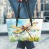 Dragonfly is flying over the grass leather tote bag