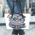 Grey owl with big eyes wearing glasses and graduation hat holding leather tote bag