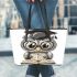 Grey owl with big eyes wearing glasses and graduation hat holding leather tote bag