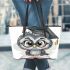 Grey owl with big eyes wearing glasses and graduation hat holding leather tote bag