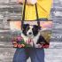 Black and white border collie sits in the foreground amidst blooming flowers leather tote bag