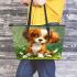 Cute brown and white puppy sits on the grass leather tote bag