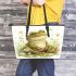 Cute frog sitting on the ground with flowers leaather tote bag