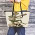 Green frog playing the banjo on top of human skull leaather tote bag