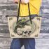 Green frog playing the banjo on top of human skull leaather tote bag