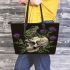 Green frog sitting on top of an skull with purple thistles growing leaather tote bag