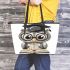 Grey owl with big eyes wearing glasses and graduation hat holding leather tote bag