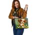 Cute brown and white puppy sits on the grass leather tote bag