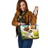 Cute cartoon puppy sitting on the grass leather tote bag