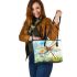 Dragonfly is flying over the grass leather tote bag