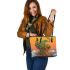 Green frog sitting on top of an island with trees and flowers leaather tote bag