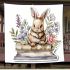 Baby rabbit sitting on top of books surrounded by flowers blanket