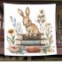 Rabbit sitting on top of books surrounded by flowers blanket