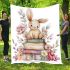 Baby rabbit sitting on top of books surrounded by flowers blanket