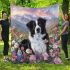Black and white border collie sits in the foreground amidst blooming flowers blanket