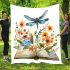 Dragonfly sitting on an open book surrounded by flowers blanket