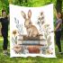 Rabbit sitting on top of books surrounded by flowers blanket