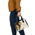 Abstract composition of circles and lines in gold shoulder handbag