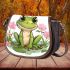 Cute cartoon frog sitting on the ground with pink flowers saddle bag