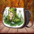 Cute frog sitting on the grass with flowers saddle bag