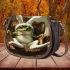 Cute green frog sitting in an armchair wearing white bunny slippers saddle bag