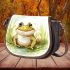 Cute happy frog in the grass near water saddle bag