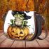 Frog wearing a black witch's hat sitting on top of a halloween pumpkin saddle bag