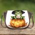 Frog wearing a black witch's hat sitting on top of a halloween pumpkin saddle bag