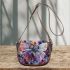 Colored butterfly surrounded by vibrant flowers saddle bag