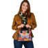 Colored butterfly surrounded by vibrant flowers shoulder handbag